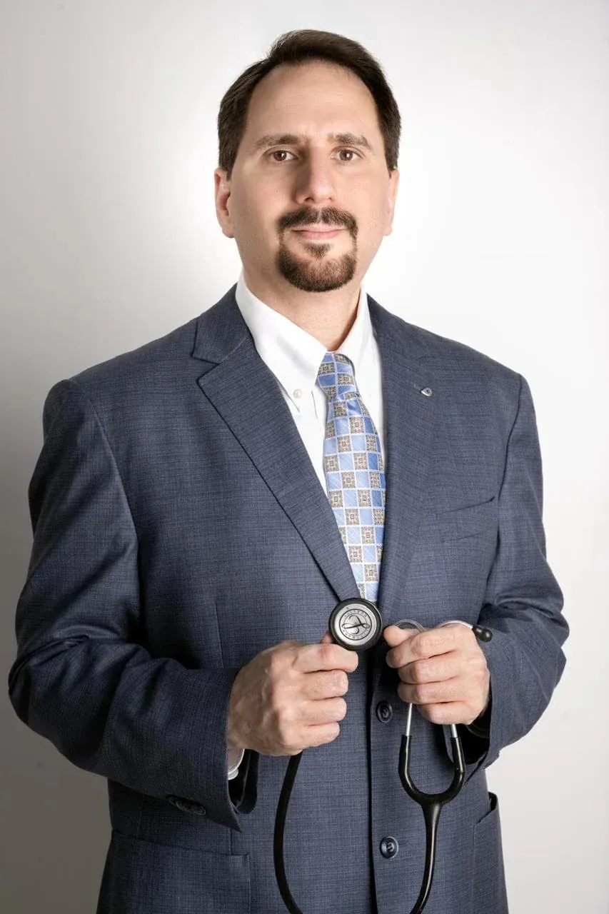 Dr. Mohammad Fawzi Katranji in a suit, holding a stethoscope